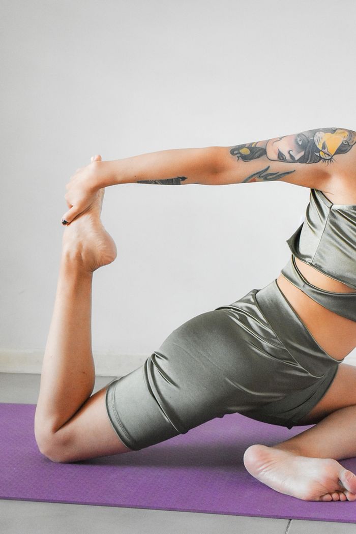 gallery-6 Female athlete in sportswear practicing a stretching pose on a yoga mat.